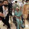 Keith Davis (centre) is whisked away and prevented from talking to reporters at Samitivej Srinakarin Hospital in Bangkok, Thailand, on Thursday.