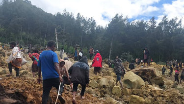 In this photo provides the International Organization for Migration, people cross over the landslide area to get to the other side in Yambali village, Papua New Guinea, Friday, May 24, 2024. More than 100 people are believed to have been killed in the landslide that buried a village and an emergency response is underway, officials in the South Pacific island nation said. The landslide struck Enga province, about 600 kilometers (370 miles) northwest of the capital, Port Moresby, at roughly 3 a.m., Australian Broadcasting Corp. reported. (Benjamin Sipa/International Organization for Migration via AP)