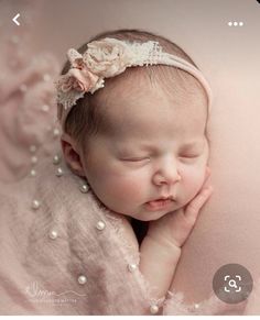 a newborn baby is sleeping with her head on her hands and wearing a pink dress