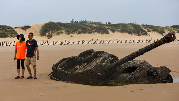 People take pictures with an abandoned American M18 army tank sitting in the sand at Ou Cuo Beach in Kinmen.