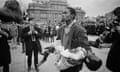 A man holding a papier-mache body, with photographers and one of the lions of Nelson's column in the background