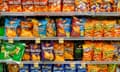 Four grocery-store shelves filled with brightly colored bags of Doritos, mostly in shades of orange.