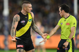 A wired-up umpire explains a decision to Dustin Martin.