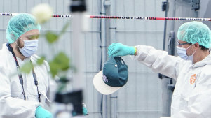 A forensic police officer work holds a cap at the scene of a knife attack at the market square in Mannheim, Germany.