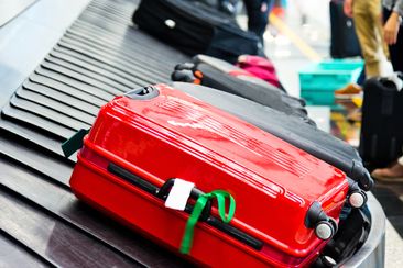 Luggages moving on airport conveyor belt. suitcase with ribbon