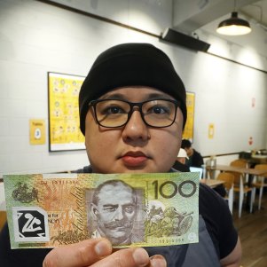 Philip Leong, from TWS Gai Wong chicken restaurant, holds a counterfeit $100 note at his restaurant in North Melbourne.