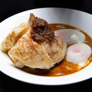 Roti banjir - roti bread in curry sauce with two soft-boiled eggs and sambal.