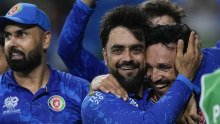 Afghanistan’s captain Rashid Khan embraces teammate Gulbadin Naib.