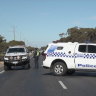 Two police vehicles guard the crash scene.