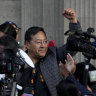 Bolivian President Luis Arce raises a clenched fist surrounded by supporters and media, outside the government palace in La Paz, Bolivia.