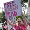 Supporters of Karen Read display signs to passing cars near court.