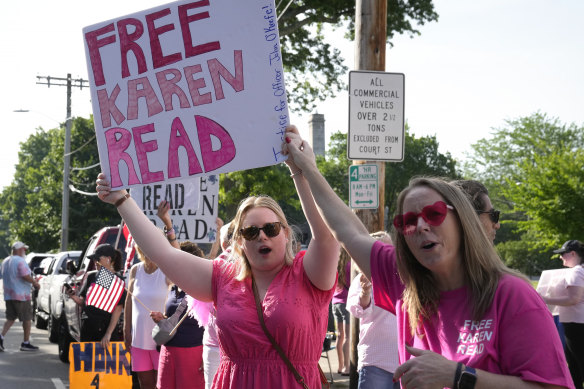 Supporters of Karen Read display signs to passing cars near court.