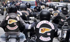 A gang of motorcyclists can be seen all wearing helmets and black jackets that say 'Hells Angels'