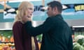 A color still of an older white woman and a younger white man appearing about to kiss in the vegetable section of a grocery store.