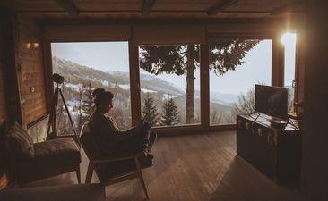 Photo of a young woman enjoying moments alone and reading news online, during her winter vacation in the mountains