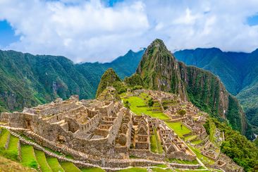 Machu Picchu, Aguas Calientes, Peru: Machu Picchu is a 15th-century Inca citadel located in the Eastern Cordillera of southern Peru on a 2,430-meter (7,970 ft) mountain ridge. It is located in the Machupicchu District within Urubamba Province  above the Sacred Valley, which is 80 kilometers (50 mi) northwest of Cusco. The Urubamba River flows past it, cutting through the Cordillera and creating a canyon with a tropical mountain climate. Most recent archaeologists believe that Machu Picchu was co