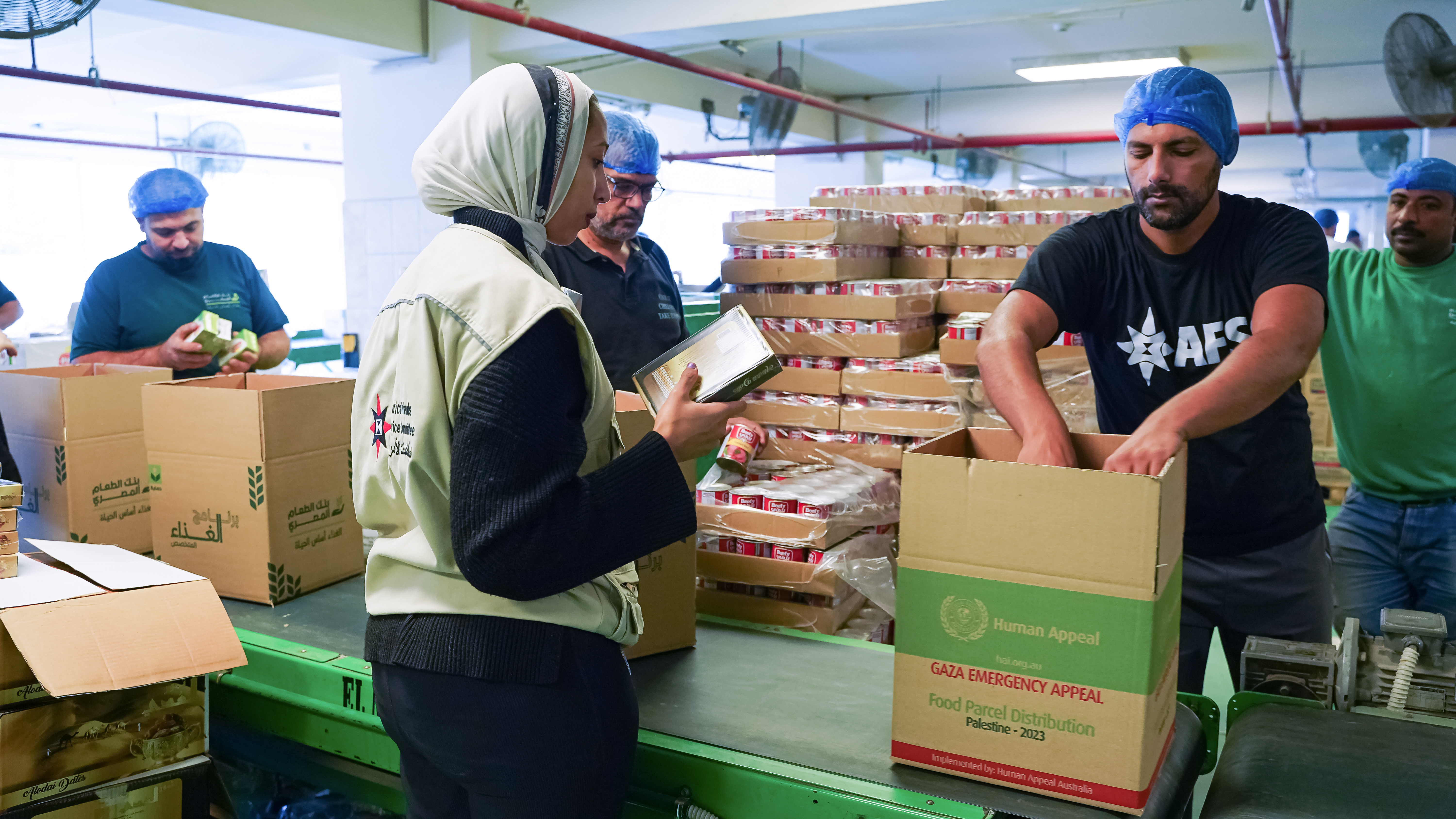 A man packs a box while someone with a clipboard looks on