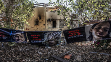 Banners showing members of the Shoham family that were abducted by Hamas on October 7th outside their damaged home in Kibbutz Beeri.