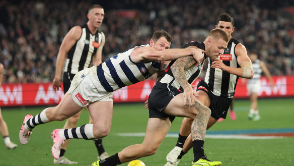 Jordan De Goey of the Magpies is challenged by Patrick Dangerfield of the Cats.