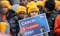 Protesters wearing yellow hats protest in favor of cancelling student debt, with one holding a sign