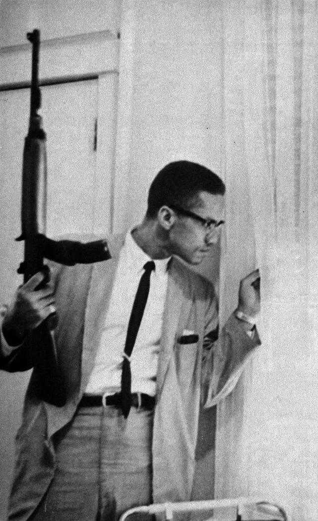 r/pics - Malcolm X holding a Rifle while guarding his family, 1964. 