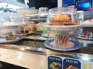 Conveyor belt sushi on plates with plastic covers at a restaurant in Seoul, South Korea.