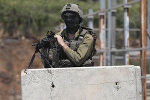 An Israeli soldier secures the entrance to the West Bank city of Hebron, a day after a deadly shooting attack that killed an Israeli woman and seriously wounded a man near the city, Tuesday, Aug. 22, 2023. The Israeli military said that overnight, its forces conducted large-scale searches and arrest raids throughout the West Bank, interrogating 20 Palestinians, confiscating illegal vehicles and arresting an additional 13 suspects near Hebron.