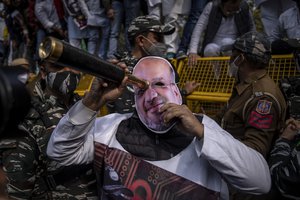 File - An opposition Congress party worker, wearing a mask of Amit Shah, India's home minister, looks through a scope during a Pegasus spyware protest accusing Prime Minister Narendra Modi's government of using military-grade spyware to monitor political opponents, journalists and activists, in New Delhi, India, Wednesday, Feb. 2, 2022.