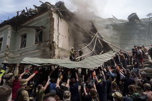 FILE - Emergency services work at the site of Okhmatdyt children's hospital hit by Russian missiles, in Kyiv, Ukraine, Monday, July 8, 2024. For Ukrainian competitors in Paris for the Olympics, joy goes hand in hand with sorrow. Athletes are striving to enjoy the dream of competing at one of the world’s most prestigious sports events while carrying the burden of the war back home.