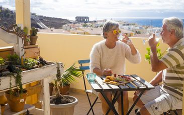 nice couple of retired adult stay together on the rooftop terrace eating and drinking some food and drin