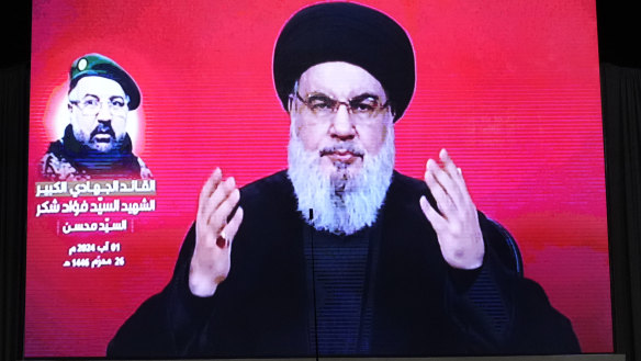 Hezbollah fighters stand behind the coffin of their top commander Fuad Shukr, who was killed by an Israeli airstrike as Hezbollah leader Sayyed Hassan Nasrallah speaks through a screen during Shukur’s funeral.