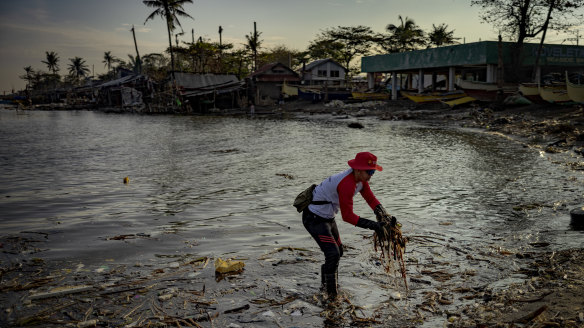 Workers collect debris, some stained with oil from the sunken tanker MT Terra Nova, along a beach in Noveleta, Cavite province, Philippines.