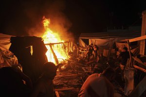 Palestinians react to fire from an Israeli strike that hit a tent area in the courtyard of Al Aqsa Martyrs hospital in Deir al Balah, Gaza Strip, Sunday, Aug. 4, 2024. The strike killed several people including a woman and injured others, health officials confirmed.