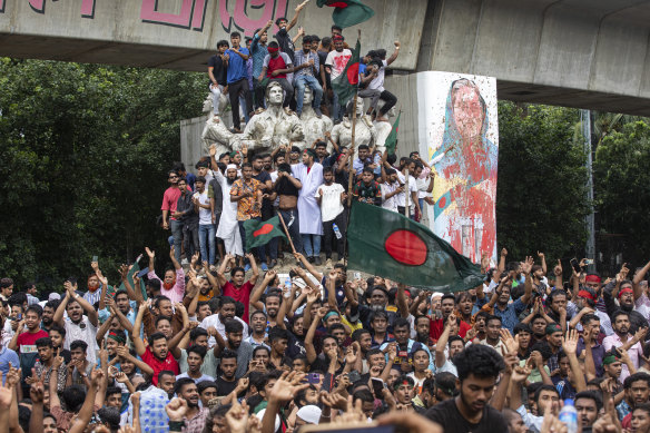 Protesters climb a public monument in Dhaka as they celebrate the news of Prime Minister Sheikh Hasina’s resignation.