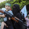 A supporter of the Islamist Hamas movement carries her son, who holds a machine gun toy during a protest in the southern port city of Sidon, Lebanon.