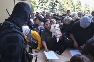 Evacuated people in the Kursk region queue to fill out the form for humanitarian aid at a humanitarian aid distribution center in Kursk, Russia, Wednesday, Aug. 14, 2024.