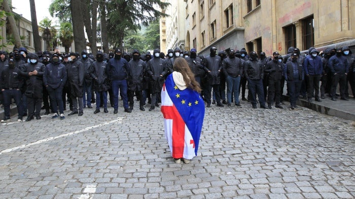 A demonstrator draped with the Georgian national and EU flags stands in front of police who are blocking the way to the parliament building, during a protest against the “foreign agent” law in Tbilisi, Georgia, May 14, 2024.