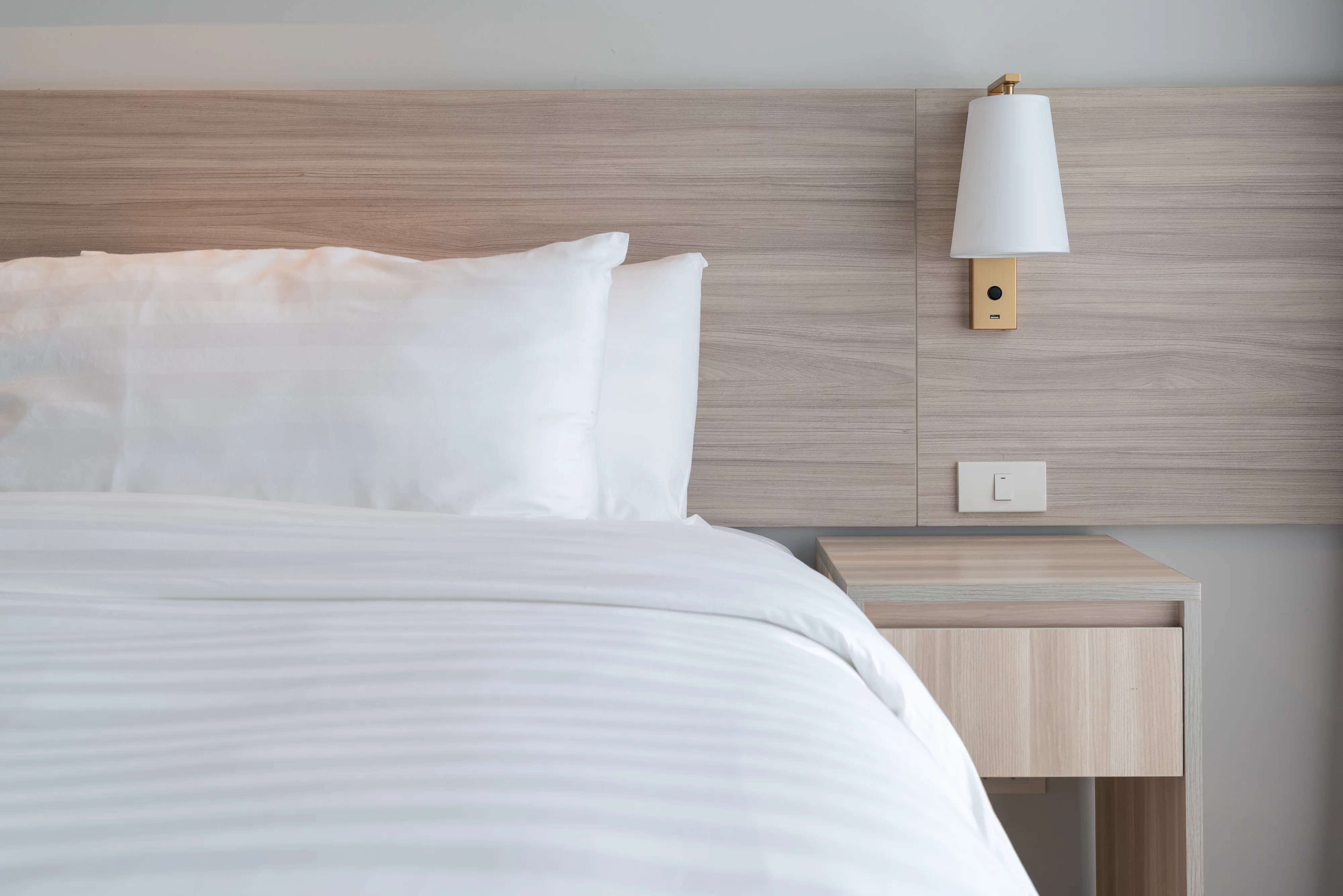 Hotel room with bed, wall sconce and nightstand