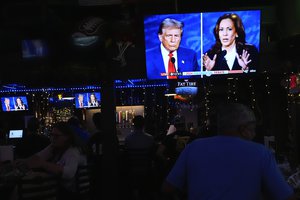 People watch TV screens showing a debate between Democratic presidential nominee Vice President Kamala Harris, right, and Republican presidential nominee former President Donald Trump, at Sports Grill Kendall, where the Miami-Dade Democratic Hispanic Caucus had organized a watch party, Tuesday, Sept. 10, 2024, in Miami.