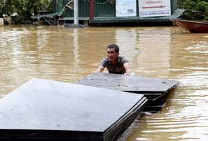 A man pushes a stack of plyboards in flood following Typhoon Yagi in Hanoi, Vietnam on Tuesday, Sept. 10, 2024.