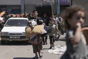 File - Palestinians evacuate a school that had been their shelter, in eastern Deir al-Balah, Gaza Strip, Friday, Aug. 16, 2024, after the Israeli military dropped leaflets asking civilians to evacuate from the area and northern Khan Younis, saying forces plan to respond to rocket fire that targeted Israel.