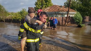 In this photo released by the Romanian Emergency Services Galati (ISU Galati), a rescuer carries a woman in Pechea, Romania, Saturday, Sept. 14, 2024 after torrential rainstorms left scores of people stranded in flooded areas.