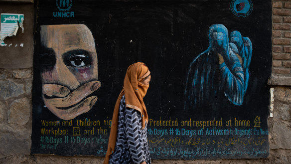 A woman walks past a mural calling for women and children’s rights in Bamian, Afghanistan.