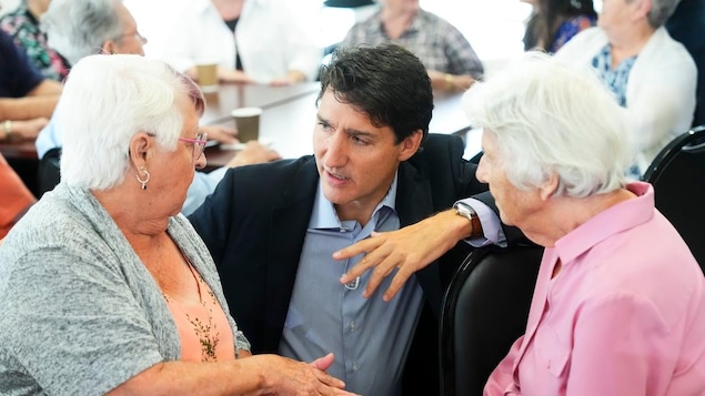 Two elderly women in conversation with Justin Trudeau.