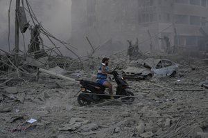 A man rides his scooter as he drives on the debris of destroyed buildings that were hit by Israeli airstrikes in Dahiyeh, Beirut, Lebanon, Sunday, Oct. 6, 2024.