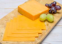 Blocks and slices of yellow American cheese arranged on a wooden cutting board