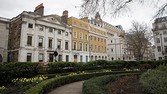 Daffodils flower in garden near white stucco and yellow brick residential properties on Cavendish Square in London