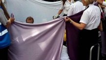 Handout photo taken from the Twitter feed of @rajjohal7 of ambulance crews holding up sheets to give privacy to a young mother who gave birth to a girl outside Primark on New Street, Birmingham, at around 2pm today.