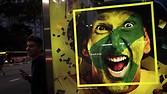 A man stands next to a photo of a Brazil soccer fan painted with the colours of his country at a bus stop in Paulista Avenue, the financial centre of Sao Paulo, June 2, 2014. The city of Sao Paulo will host the opening match of the 2014 Brazil World Cup. REUTERS/Nacho Doce (BRAZIL - Tags: SPORT SOCCER WORLD CUP SOCIETY)