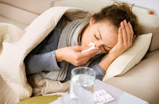 Woman blowing her nose and clutching her head